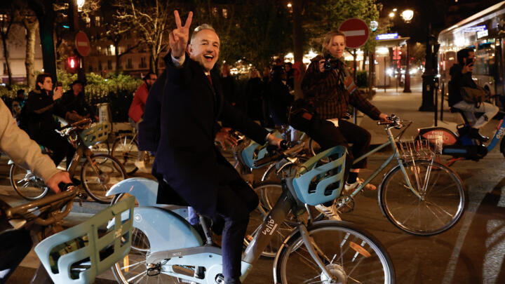 Emmanuel Gregoire makes a V sign as he rides a Velib' public bike-sharing bicycle heading to Paris townhall.