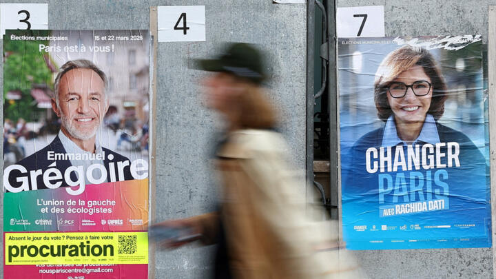 A woman walks past electoral posters of Paris mayoral election candidates Emmanuel Grégoire, for the Socialist party and head of the "left-wing coalition" list (La Gauche unie), and Rachida Dati, supported by Les Républicains (LR) and the MoDem parties, displayed on electoral campaign panel boards ahead of the second round of the Paris municipal in Paris, France, March 20, 2026.