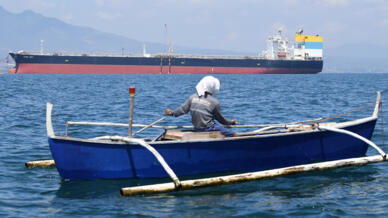 A fisherman travels past the Sara Sky, which last week arrived in the Philippines bearing crude oil from Russia
