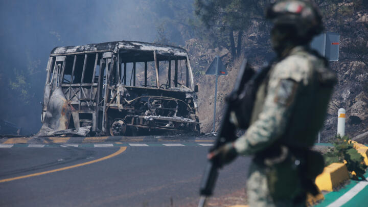 A soldier stands guard by a charred vehicle in Cointzio, Michoacan state, Mexico.
