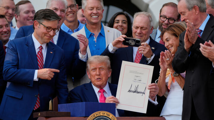 US President Donald Trump holds his signed bill of tax breaks and spending cuts at the White House, July 4, 2025, surrounded by members of Congress.