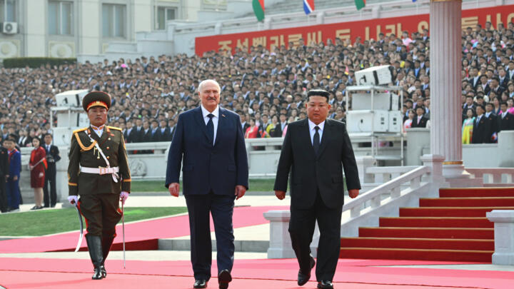 North Korea's leader Kim Jong Un, right, and Belarusian President Alexander Lukashenko, center, attend an official meeting ceremony.